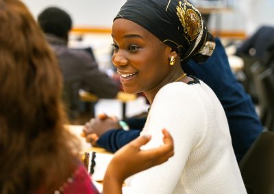 Community members in formal attire laughing and connecting around decorated tables at the Community Gala 2025.