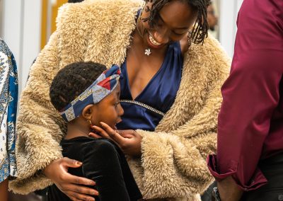 Community members in formal attire laughing and connecting around decorated tables at the Community Gala 2025.