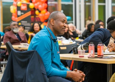 Community members in formal attire laughing and connecting around decorated tables at the Community Gala 2025.