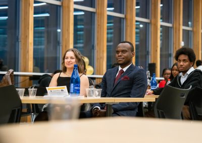 Community members in formal attire laughing and connecting around decorated tables at the Community Gala 2025.