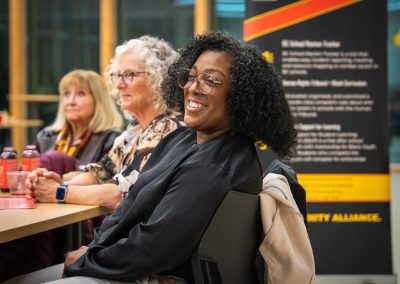 Community members in formal attire laughing and connecting around decorated tables at the Community Gala 2025.