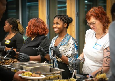 Community members in formal attire laughing and connecting around decorated tables at the Community Gala 2025.