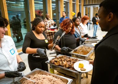 Community members in formal attire laughing and connecting around decorated tables at the Community Gala 2025.