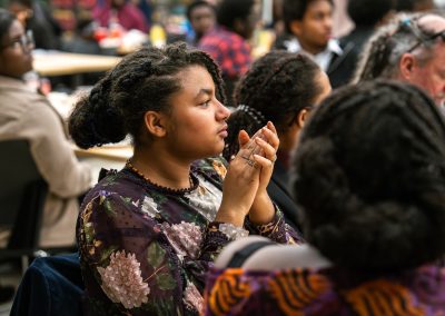 Community members in formal attire laughing and connecting around decorated tables at the Community Gala 2025.
