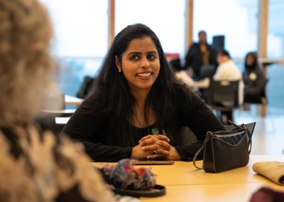 Community members in formal attire laughing and connecting around decorated tables at the Community Gala 2025.