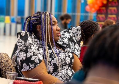 Community members in formal attire laughing and connecting around decorated tables at the Community Gala 2025.