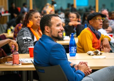 Community members in formal attire laughing and connecting around decorated tables at the Community Gala 2025.