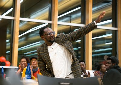 Community members in formal attire laughing and connecting around decorated tables at the Community Gala 2025.