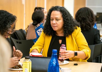 Community members in formal attire laughing and connecting around decorated tables at the Community Gala 2025.