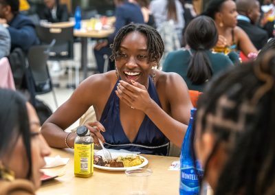 Community members in formal attire laughing and connecting around decorated tables at the Community Gala 2025.