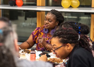 Community members in formal attire laughing and connecting around decorated tables at the Community Gala 2025.