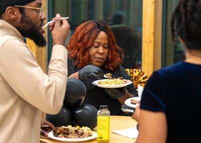 Community members in formal attire laughing and connecting around decorated tables at the Community Gala 2025.