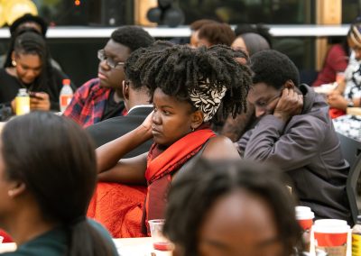 Community members in formal attire laughing and connecting around decorated tables at the Community Gala 2025.