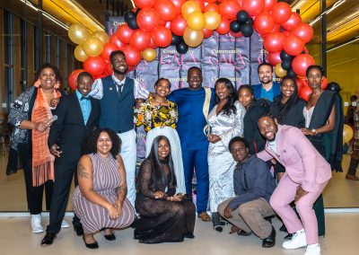 Community members in formal attire laughing and connecting around decorated tables at the Community Gala 2025.
