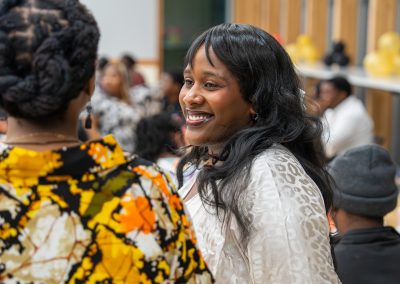 Community members in formal attire laughing and connecting around decorated tables at the Community Gala 2025.