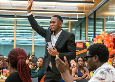Community members in formal attire laughing and connecting around decorated tables at the Community Gala 2025.