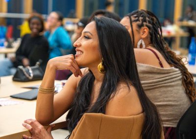 Community members in formal attire laughing and connecting around decorated tables at the Community Gala 2025.