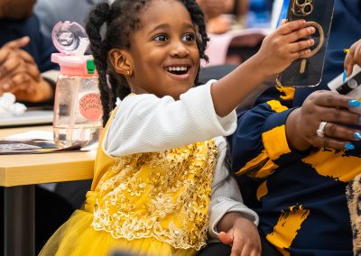 Community members in formal attire laughing and connecting around decorated tables at the Community Gala 2025.