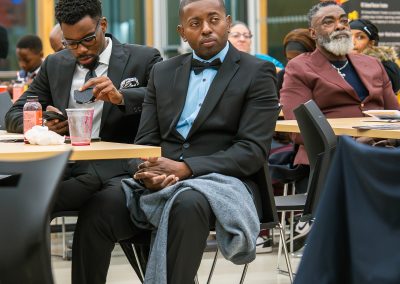 Community members in formal attire laughing and connecting around decorated tables at the Community Gala 2025.