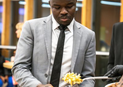 Community members in formal attire laughing and connecting around decorated tables at the Community Gala 2025.