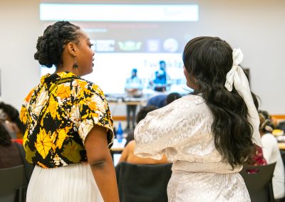 Community members in formal attire laughing and connecting around decorated tables at the Community Gala 2025.