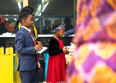 Community members in formal attire laughing and connecting around decorated tables at the Community Gala 2025.