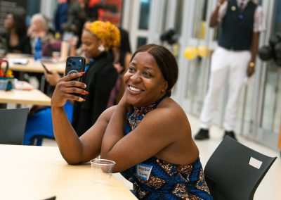 Community members in formal attire laughing and connecting around decorated tables at the Community Gala 2025.