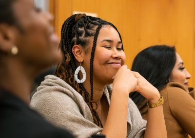 Community members in formal attire laughing and connecting around decorated tables at the Community Gala 2025.