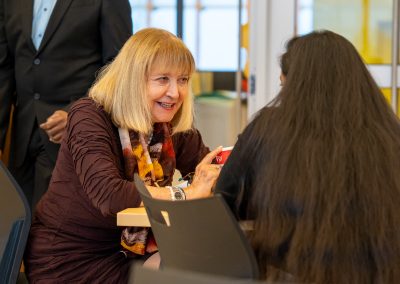 Community members in formal attire laughing and connecting around decorated tables at the Community Gala 2025.