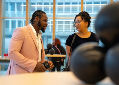Community members in formal attire laughing and connecting around decorated tables at the Community Gala 2025.