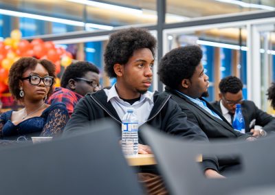 Community members in formal attire laughing and connecting around decorated tables at the Community Gala 2025.