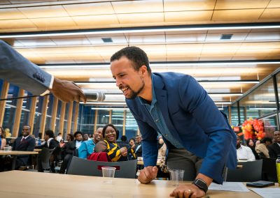 Community members in formal attire laughing and connecting around decorated tables at the Community Gala 2025.