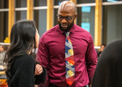 Community members in formal attire laughing and connecting around decorated tables at the Community Gala 2025.