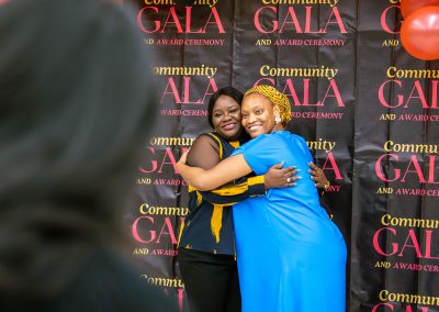 Community members in formal attire laughing and connecting around decorated tables at the Community Gala 2025.