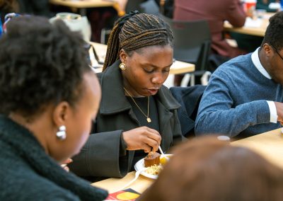 Community members in formal attire laughing and connecting around decorated tables at the Community Gala 2025.