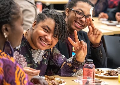 Community members in formal attire laughing and connecting around decorated tables at the Community Gala 2025.