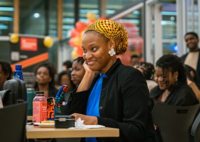 Community members in formal attire laughing and connecting around decorated tables at the Community Gala 2025.