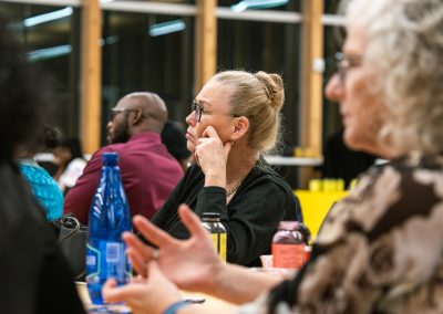 Community members in formal attire laughing and connecting around decorated tables at the Community Gala 2025.