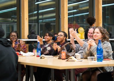 Community members in formal attire laughing and connecting around decorated tables at the Community Gala 2025.