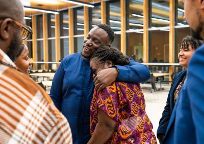 Community members in formal attire laughing and connecting around decorated tables at the Community Gala 2025.