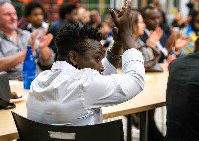 Community members in formal attire laughing and connecting around decorated tables at the Community Gala 2025.