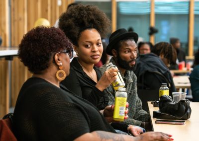 Community members in formal attire laughing and connecting around decorated tables at the Community Gala 2025.