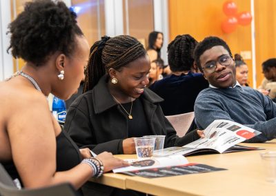 Community members in formal attire laughing and connecting around decorated tables at the Community Gala 2025.