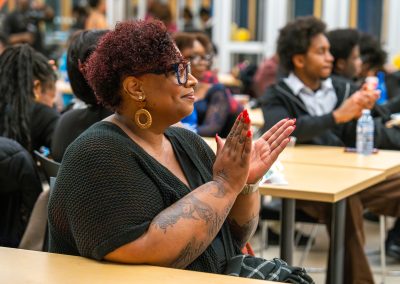 Community members in formal attire laughing and connecting around decorated tables at the Community Gala 2025.
